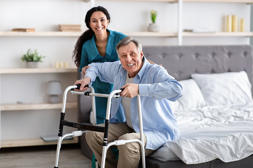 female nurse helping elderly man get up at nursing home