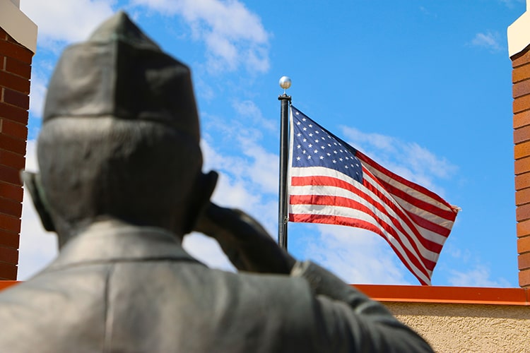 veteran statue saluting american flag