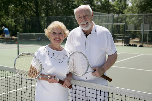 elderly couple playing tennis at a senior community